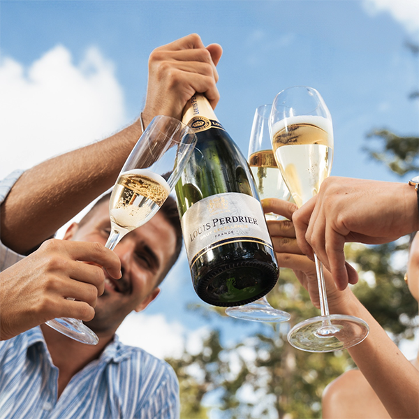 Brindis con botella de Louis Perdrier Brut y copas de vino espumoso al aire libre
